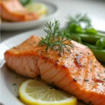 Perfectly baked salmon fillets topped with garlic herb butter sauce and lemon slices, served on a baking sheet